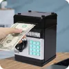 A hand inserts a dollar bill into a black and silver electronic piggy bank with a keypad. Náhled obrázku produktu