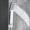 A close-up shot of a modern chrome shower head spraying water against a textured gray tiled wall. Podgląd zdjęcia produktu