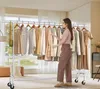 A woman is standing next to a clothing rack filled with clothes, looking at the clothes. Náhled obrázku produktu