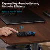 A hand is shown interacting with a small black keyboard-like device with a blue ring on a wooden desk, with a large black tablet in the background. Anteprima dell’immagine prodotto