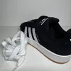 A black Adidas Campus shoe with white laces next to it, on a white background. Voir les images du produit