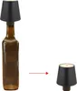 A brown glass bottle with a black lampshade on top, and a separate black lampshade on the right. Produktbild-Vorschau
