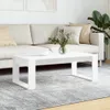 A white coffee table is placed on a rug in front of a sofa.
