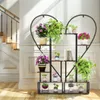 A heart-shaped plant stand filled with various plants and books, placed in a well-lit room with a staircase in the background. Produktbild-Vorschau