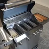 A close-up, slightly angled view of the interior of a stainless steel grill with its lid open. Produktbild-Vorschau