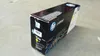 A black box for an HP toner cartridge sits on a concrete floor. Náhľad obrázku produktu