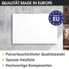 A white panel is mounted on a textured gray wall, with a brick wall and furniture visible in the background. A 'Made in EU' logo is present. Produktbild-Vorschau