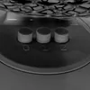 Close-up of three buttons with numbers 0, 1, and 2 below them, set on a gray surface. A portion of a fan grille is visible at the top. Produktbild-Vorschau
