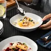 A person is eating a bowl of yogurt with fruit and granola, with another bowl of dessert in the foreground. Produktbild-Vorschau