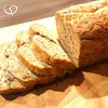A loaf of bread, sliced, on a wooden cutting board. Produktbild-Vorschau