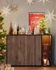 A Christmas-themed display on a wooden sideboard, featuring a decorated tree, festive decorations, and a framed poster. Produktbild-Vorschau