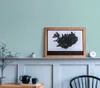 A shelf with a framed map of Iceland, a teapot and cup, and a small plant. Produktbild-Vorschau