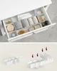 A white drawer organizer with various bathroom items and an illustration of how the organizer pieces assemble. Náhled obrázku produktu