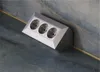 A silver 3-socket power strip is mounted on a wall with a marble-like texture. Produktbild-Vorschau