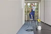 A person is using a paint sprayer on a ladder to paint a wall in a room. Náhľad obrázku produktu