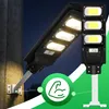 Two solar street lights are shown, one mounted on a concrete pillar and another on a white pole. A green circle with a muscular arm icon is overlaid on the image. Anteprima dell’immagine prodotto