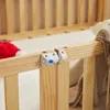 A close-up view of a wooden crib railing with a safety latch mechanism attached. Produktbild-Vorschau
