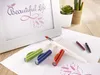 A white framed picture with calligraphy and decorative elements, along with calligraphy pens and ink cartridges, are arranged on a wooden desk. Voir les images du produit