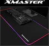 A gaming mousepad with RGB lighting, a keyboard, and a monitor stand on a black surface. Produktbild-Vorschau