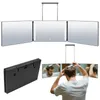 A man is using a tri-fold mirror with LED lights to style his hair. Produktbild-Vorschau