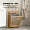 A bamboo laundry basket with a removable fabric bin is shown in a bathroom setting next to a white cabinet and a hanging bathrobe. Podgląd zdjęcia produktu