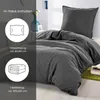 A dark gray duvet cover and pillowcase set laid out on a bed, with text overlays describing the package contents. Náhled obrázku produktu