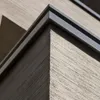 A close-up view of a building corner with textured concrete and a dark metal trim. Produktbild-Vorschau