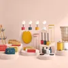 A collection of bathroom accessories and home decor items displayed on pedestals against a light pink background. Anteprima dell’immagine prodotto