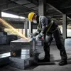 A construction worker is using an angle grinder to cut metal ductwork in an unfinished building. Náhľad obrázku produktu
