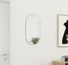 A mirror hanging on a white wall next to a door and a framed picture. Produktbild-Vorschau