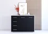 A modern black and white dresser with decorative items on top, set against a white wall and a slatted wooden panel. Voir les images du produit