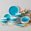 A collection of blue and white ceramic dishes arranged on a light gray surface. Produktbild-Vorschau