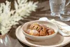 A bowl of pastries on a wooden tray, with a pitcher and glass of water in the background. Produktbild-Vorschau