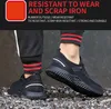 A person wearing black safety shoes with red and black striped socks, standing on a surface of metal shavings. Produktbild-Vorschau