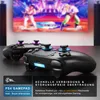 Two black game controllers are placed on a dark surface in front of a blurred television screen displaying a video game. Produktbild-Vorschau
