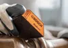 A gloved hand holds a Bosch sanding block over a metal object. Produktbild-Vorschau