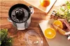 A citrus juicer is shown on a wooden table with oranges being prepared for juicing. Podgląd zdjęcia produktu