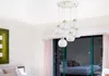 A modern pendant light fixture with multiple white glass globes hangs in a well-lit room, with a glimpse of a bedroom through a glass door in the background. Produktbild-Vorschau