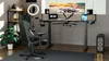 A modern gaming or home office setup with a height-adjustable desk, gaming chair, and multiple monitors. Produktbild-Vorschau