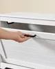 A person's hand is opening a drawer on a white piece of furniture. Produktbild-Vorschau