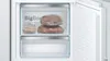 The inside of a refrigerator or freezer compartment with two drawers, one of which contains two loaves of bread in plastic bags. The door of the appliance is open. Produktbild-Vorschau