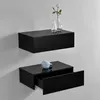 Two black floating shelves mounted on a light gray wall. The top shelf holds two clear glass vases, one with a white rose. The bottom shelf has a light blue decorative object and its drawer is partially open. Voir les images du produit