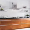 A modern kitchen with a stainless steel range hood mounted on a white brick wall above a stovetop and wooden cabinets. Produktbild-Vorschau