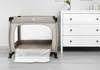 A beige playpen is shown in a room next to a white dresser. Produktbild-Vorschau
