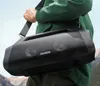 A person carrying a portable speaker over their shoulder outdoors. Náhled obrázku produktu
