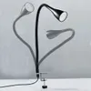 A black adjustable desk lamp with a clamp base is shown against a light gray and white background. Ghosted images of the lamp in different positions are visible. Anteprima dell’immagine prodotto