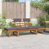 A wooden garden bench with dark gray cushions is placed on a paved patio, with a wooden fence and greenery in the background. Náhľad obrázku produktu