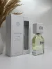 A perfume bottle and its box are displayed on a white surface with a dried plant in the background. Podgląd zdjęcia produktu