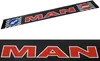 A long, black product with red and white lettering spelling out 'MAN'. There are also two traffic signs, one indicating a left turn and the other a 'no entry' sign. Produktbild-Vorschau