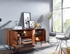 A wooden sideboard with decorative items on top and inside, placed in a room with a large window and a chair. Náhled obrázku produktu